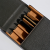 Black leather case with brown interior compartments on a light gray background