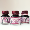 Papier Plume American Beauty Rose fountain pen ink in a glass bottle with vibrant pink and red ink, ideal for writing and calligraphy.