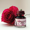 Papier Plume American Beauty Rose fountain pen ink bottle with vibrant red and pink ink inside.