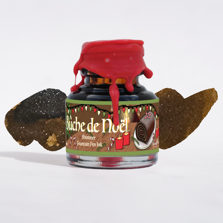 Bottle of Buche de Noël fountain pen ink with decorative elements on a white background