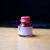 Pink fountain pen ink from Papier Plume's Loop Series, shown in a clear glass bottle with a black cap and vibrant color.