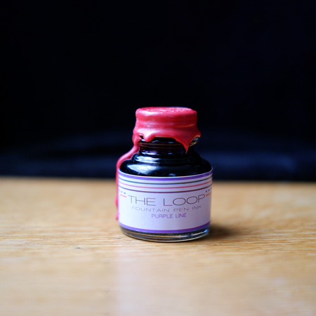 Papier Plume The Loop Series purple fountain pen ink bottle with a sleek design and vibrant ink visible inside.